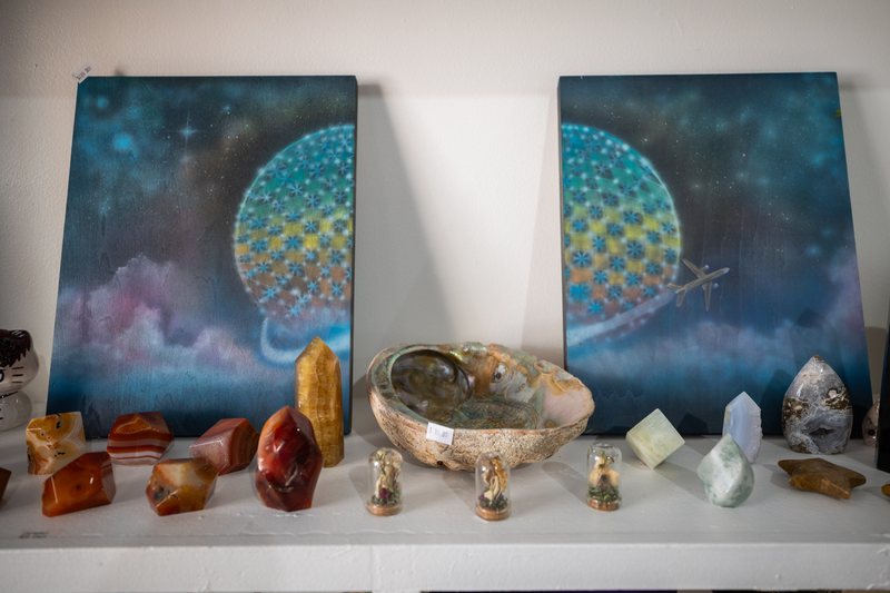 Two paintings titled Around The World by Josh Zarambo, with polished minerals in front